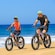 Two Guests riding electric bikes along a beach